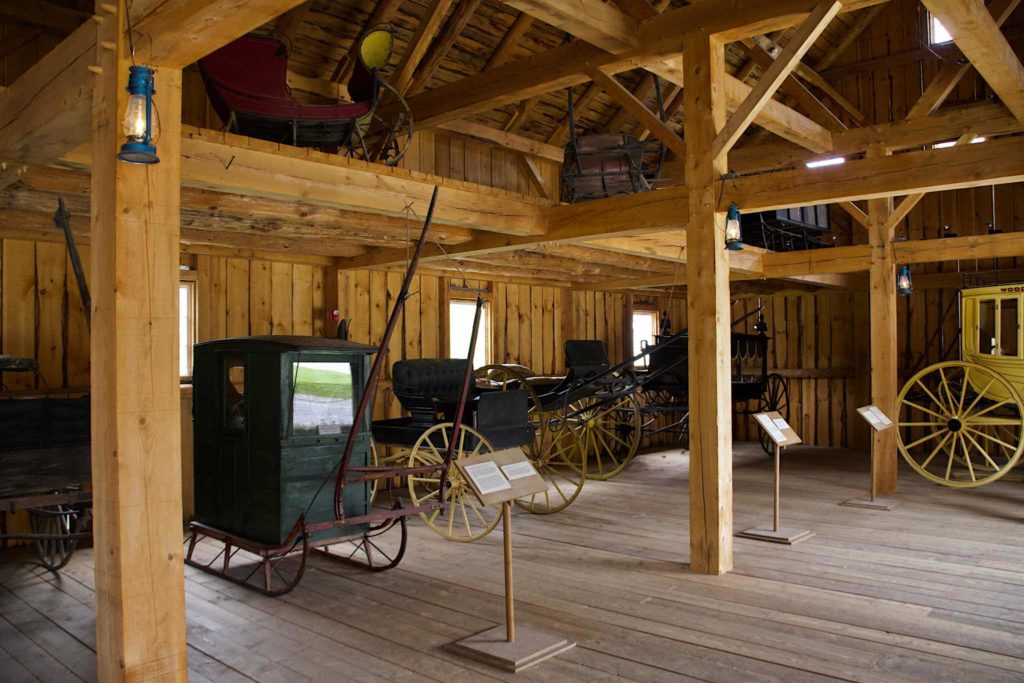 A sleigh, a wagon and a hearse inside the reproduction barn