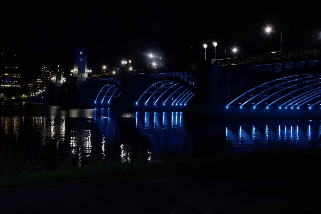 Blue lights shine from underneath the Longfellow Bridge