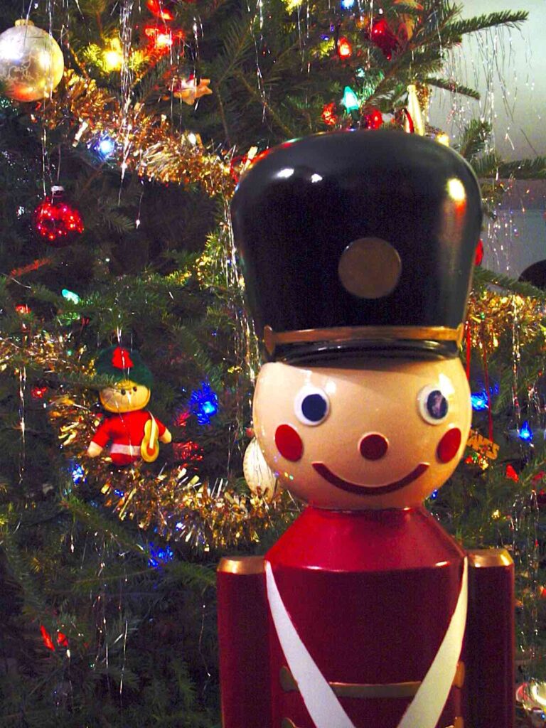 Single toy soldier in front of decorated tree