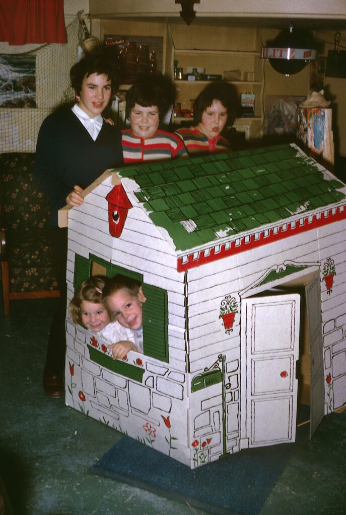 Susan with her sisters in the basement of our house, with my sister and I in a cardboard house